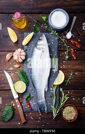 Le poisson cru, sea bass sur ardoise tableau noir. Ingrédients pour la cuisson, grill, la torréfaction. Vue d'en haut. Banque D'Images