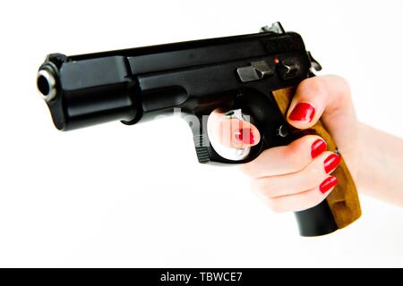 Big Black pistolet semi-automatique avec poignée en bois dans la main de petite femme avec manucure Banque D'Images