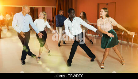 Les jeunes gens sourire active la pratique de mouvements de danse lindy hop en classe Banque D'Images