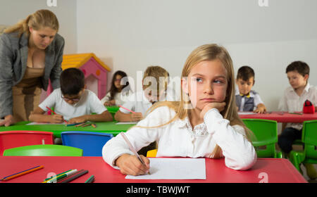 Portrait de l'écolière ennuyé assis en classe avec leurs camarades et l'enseignant Banque D'Images