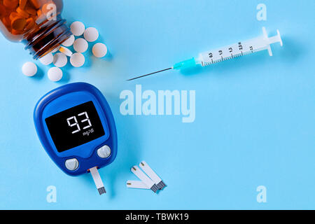 La surveillance du diabète et de la santé. Fermer jusqu'en haut Vue de glucomètre, comprimés de médicaments et de seringues sur fond bleu avec copie espace. Banque D'Images