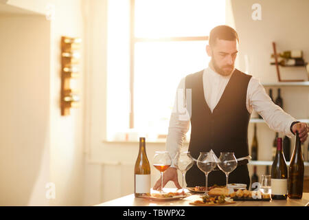 Taille portrait de sommelier professionnel Préparation à une séance de dégustation de vin dans la lumière du soleil, copy space Banque D'Images