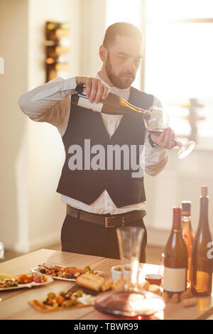 Portrait de sommelier professionnel de verser le vin tout en se préparant pour une séance de dégustation de vin dans la lumière du soleil Banque D'Images