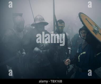 L'Escouade de combat de chevaliers médiévaux des croisés se tenir dans les armures et casques avec leurs épées et boucliers préparent à attaquer en matin brumeux. Banque D'Images