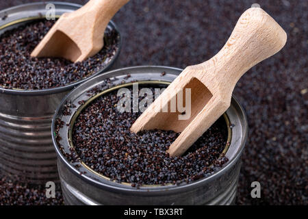 Un grain d'opium dans un peut sur une table de cuisine. Récupérer les graines de pavot et cuillère en bois sur une cuve de stockage. Fond sombre. Banque D'Images