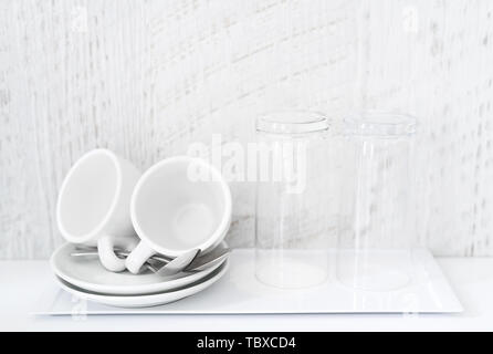 Plateau thé/café et blanc ensemble de tasses, soucoupes, cuillères à thé et verres sur la porcelaine blanche bac. logement d'hôtel. Copier l'espace. Banque D'Images