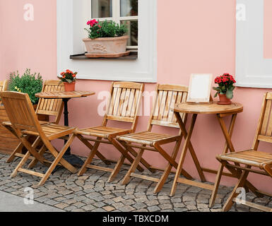 Café en plein air tables vides avec des fleurs le long d'une rue pavée de Prague. Banque D'Images