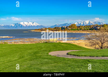 Trail et banc sur un champ avec vue sur le lac sous ciel bleu sur une journée ensoleillée Banque D'Images