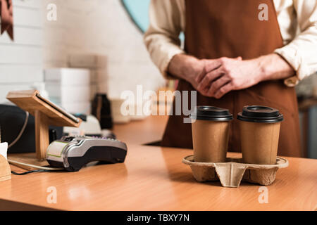 Portrait de barista brown en tablier et tasses de café à usage unique Banque D'Images