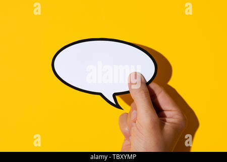 Libre de la main d'un young caucasian man holding a blank bulle sur fond jaune, avec une ombre Banque D'Images