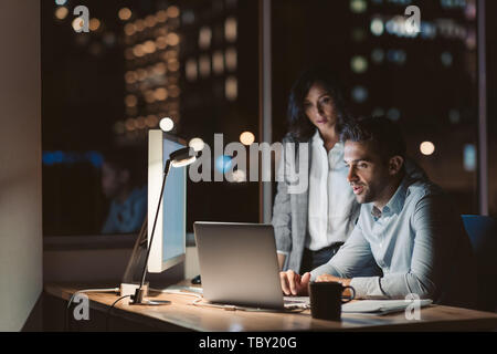 Deux autres collègues qui travaillent dans un bureau tard dans la nuit Banque D'Images