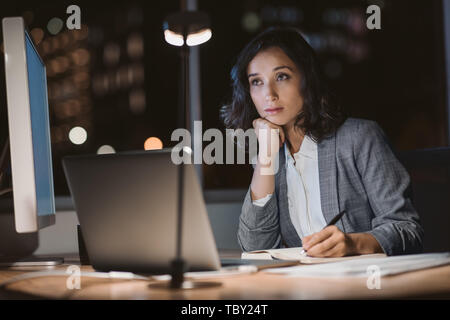 Young businesswoman looking fatigué tout en travaillant des heures supplémentaires dans un bureau Banque D'Images