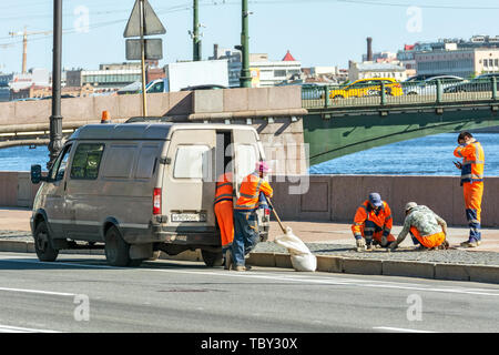 Saint-pétersbourg, Russie, le 30 mai : Cinq ouvriers en salopette orange la réparation des pavés sur la berge du fleuve Neva, 30 mai 2019. Banque D'Images