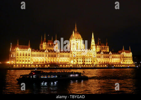 Silhouette de bateau touristique sur les rives du Danube en face de l'édifice du Parlement illuminé de Budapest, Hongrie la nuit. Banque D'Images