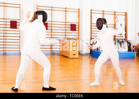 Les femmes en uniforme des mouvements pratiquant en escrime bataille Banque D'Images