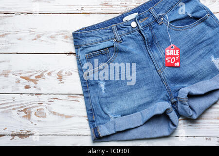 Short Jeans avec tag shopping sur fond de bois blanc Banque D'Images