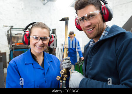 Portrait de femme tenant la flamme de gaz industriels avec collègue masculin Banque D'Images