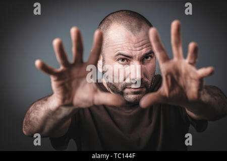 Studio portrait of Caucasian man with ouvrir les mains et bras tendus en avant. Selective focus sur le visage. Banque D'Images