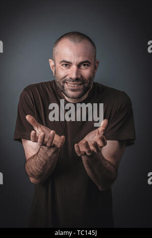 Portrait d'un homme avec l'expression satisfaite et les mains jointes devant lui. Regarder vers l'appareil photo. Banque D'Images