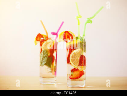 Des boissons d'été frais avec du citron, fraise et menthe et pailles colorées sur la table en bois Banque D'Images