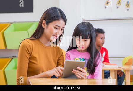 Femme Asiatique fille enseigner enseignant étudiant avec tablet computer in classe à la maternelle l'éducation préscolaire en ligne,concept Banque D'Images