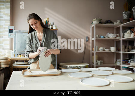 Taille portrait de jeune femme à la main de ponçage plaque en céramique dans l'atelier de poterie, copy space Banque D'Images