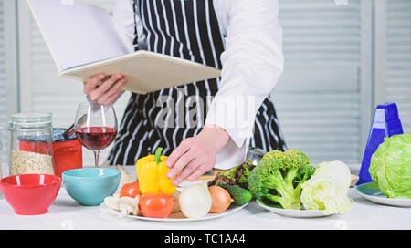 Concept d'arts culinaires. Apprendre l'homme recette. Améliorer les compétences de cuisson. Guide de cuisson ultime pour les débutants. Livre des recettes de famille. Selon recette. Chef barbu homme à la cuisson des aliments. Guy lire livre de recettes. Banque D'Images