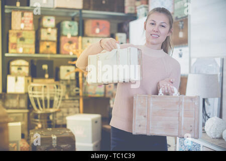 Femme avec valise en bois dans le magasin de meubles avant l'achat Banque D'Images