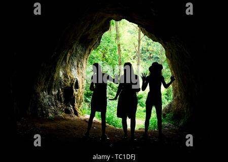 Silhouettes féminines à l'entrée de grotte naturelle dans la forêt, accueil des peuples anciens Banque D'Images