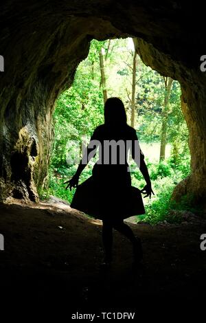 La silhouette de femme à l'entrée de grotte naturelle dans la forêt, accueil des peuples anciens Banque D'Images