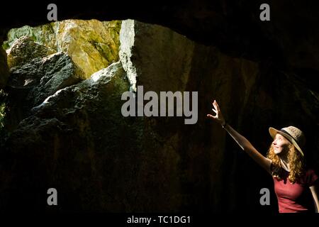 Un jeune explorateur girl à hat pointant et trou dans l'ancienne cave où le soleil va à l'intérieur Banque D'Images