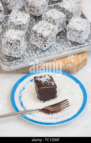 Des gâteaux de Lamington. Gâteau d'Australie. Gâteau éponge coupé en cubes enrobés d'une couche de sauce au chocolat et roulé dans la noix de coco desséchée Banque D'Images