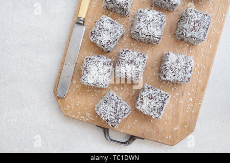 Des gâteaux de Lamington. Gâteau d'Australie. Gâteau éponge coupé en cubes enrobés d'une couche de sauce au chocolat et roulé dans la noix de coco desséchée Banque D'Images