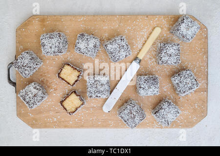 Des gâteaux de Lamington. Gâteau d'Australie. Gâteau éponge coupé en cubes enrobés d'une couche de sauce au chocolat et roulé dans la noix de coco desséchée Banque D'Images