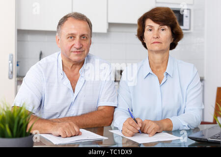 Portrait of mature couple positif au remplissage des documents table de cuisine Banque D'Images