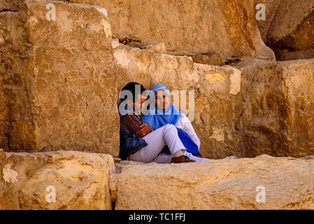 Photo : © Simon Grosset. La pyramide de Gizeh, Nécropole de Gizeh ou complexe, près du Caire, Égypte. Un couple reste à l'ombre sur les blocs de la Grande Pyramide Banque D'Images