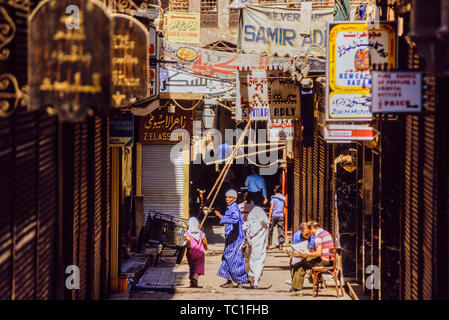 Louxor, Egypte. Une scène de rue avec des bannières publicité commerçants et deux touristes à l'extérieur d'un café en lisant un journal ou une carte. Photo : © Simon Grosset. Banque D'Images