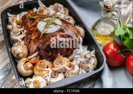 Agneau mariné avec les champignons, les épices et les herbes dans un moule en fonte sur un fond de bois. Les tomates et l'huile d'olive. La viande halal et de l'alimentation Banque D'Images