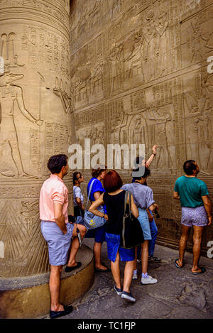 Egypte : les touristes étant illustré d'hiéroglyphes et bas-relief décoration dans un temple sur le Nil. Photo : © Simon Grosset. Archive : image numérisé à partir d'un ou Banque D'Images