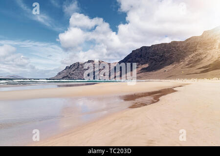 Grande plage de sable sur la plage de Famara Lanzarote, Espagne contre l'océan Atlantique, les montagnes escarpées et beau ciel Banque D'Images