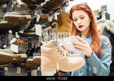 Fille dans le magasin de chaussures d'hiver choisit shopaholic. Banque D'Images