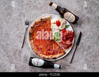 Gros plan d'une pizza jambon fumé en tranches de parme, chef de pizza italienne fine cuisine gastronomique d'un éclairage naturel de charcuterie assiette de fromage gorgonzola, bois de la bière Banque D'Images