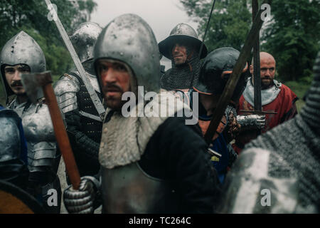 L'Escouade de combat de chevaliers médiévaux des croisés se tenir dans les armures et casques avec leurs épées et des haches. L'accent sur l'arrière. Banque D'Images