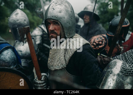 L'Escouade de combat de chevaliers médiévaux des croisés se tenir dans les armures et casques avec leurs épées et des haches. Banque D'Images