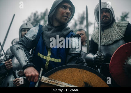 L'Escouade de combat de chevaliers médiévaux des croisés se tenir dans les armures et casques avec leurs épées et boucliers préparation de l'attaque. Banque D'Images