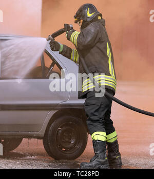 Casque de pompier courageux avec mousse utilise lors d'un accident de la route sur la voiture cassée Banque D'Images