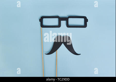 Moustache décorative et lunettes noires sur fond de papier bleu clair. Vue du dessus pour carte de vœux avec emplacement pour texte. Plat de la fête des pères Banque D'Images