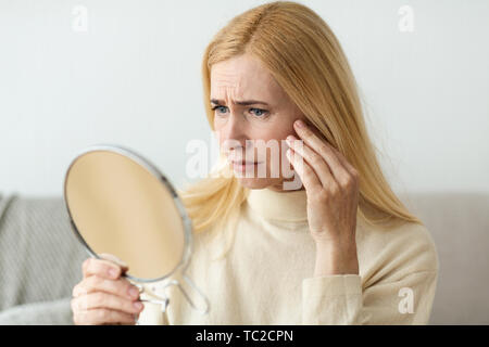 Soins de la peau anti-rides. Sad Woman Looking In Mirror Banque D'Images