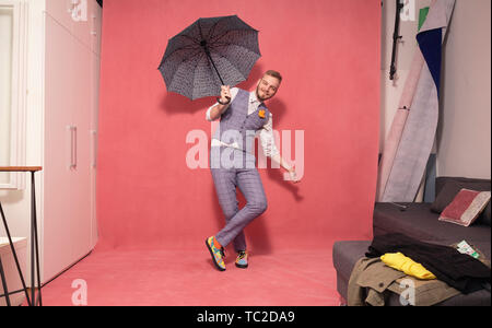 Un jeune homme, 29 ans, posant avec un parapluie ouvert à l'intérieur d'un studio. tourné en studio, fond rose. Banque D'Images