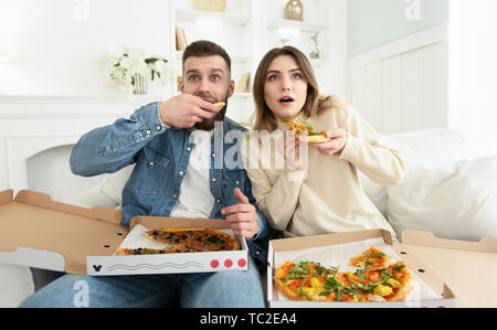 Couple millénaire Regarder Film d'horreur et Eating Pizza Banque D'Images